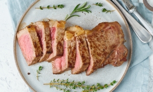 Keto ketogenic diet beef steak, striploin on gray plate on white background.