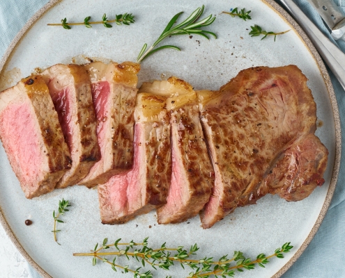 Keto ketogenic diet beef steak, striploin on gray plate on white background.