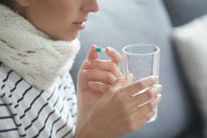 Sick woman drinking water with pills