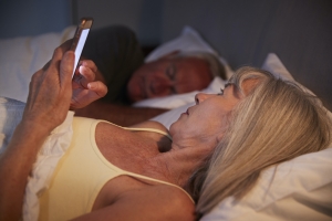 Sleepless Senior Woman In Bed At Night Using Mobile Phone