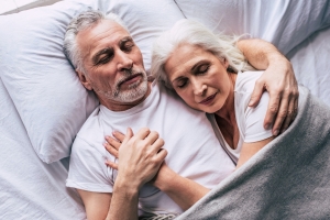 The elderly couple sleeping on the bed.